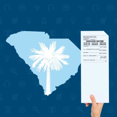 南卡罗来纳州的形状与来自州旗插入的棕榈，旁边的一个人的手拿着投票的纸张投票卡。